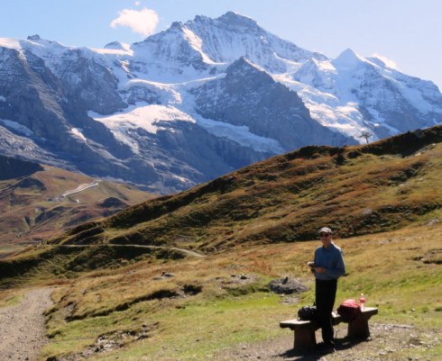 Man at a bench with mountains in background